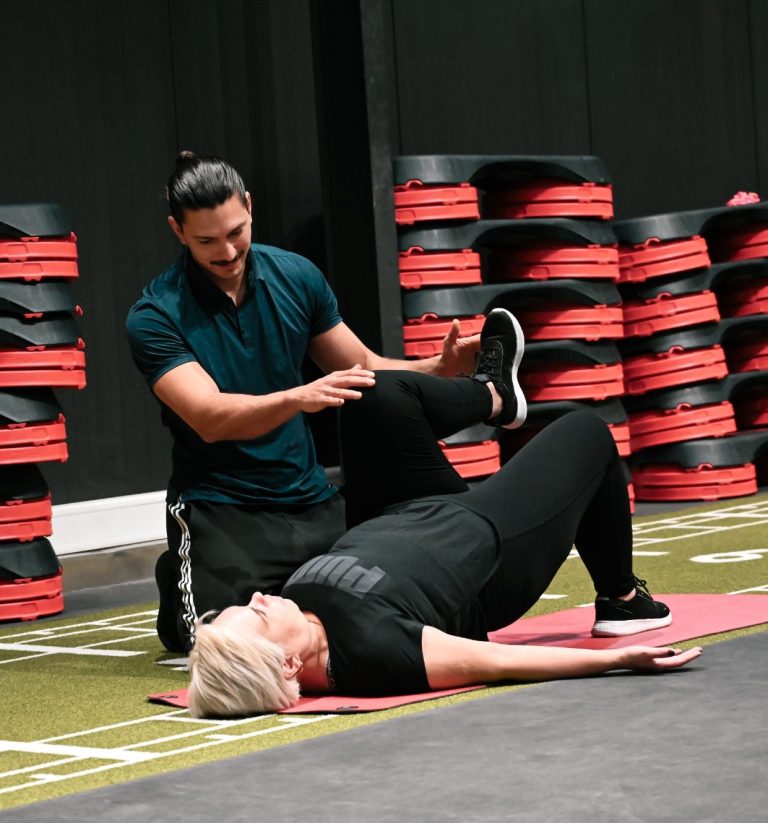 Mirko unterstützt Kundin beim Personal Training in einem Fitnessstudio.