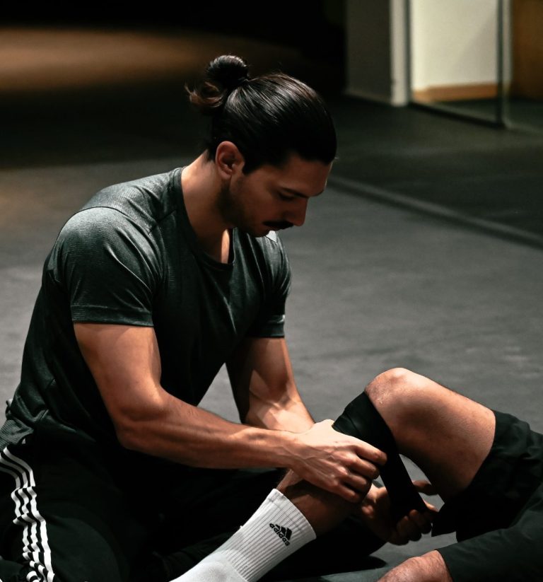 Mirko flosst das Knie eines Kunden in einem Fitnessraum.